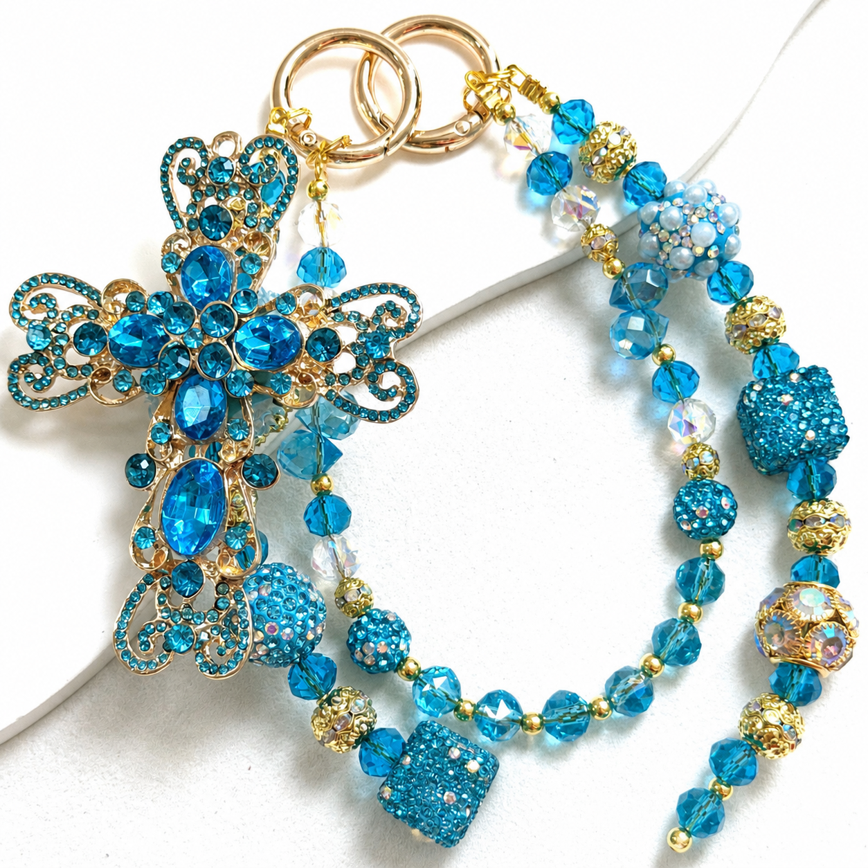 Aqua-blue beaded bag charm with a large butterfly centerpiece and layered hanging beads.