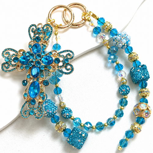Aqua-blue beaded bag charm with a large butterfly centerpiece and layered hanging beads.